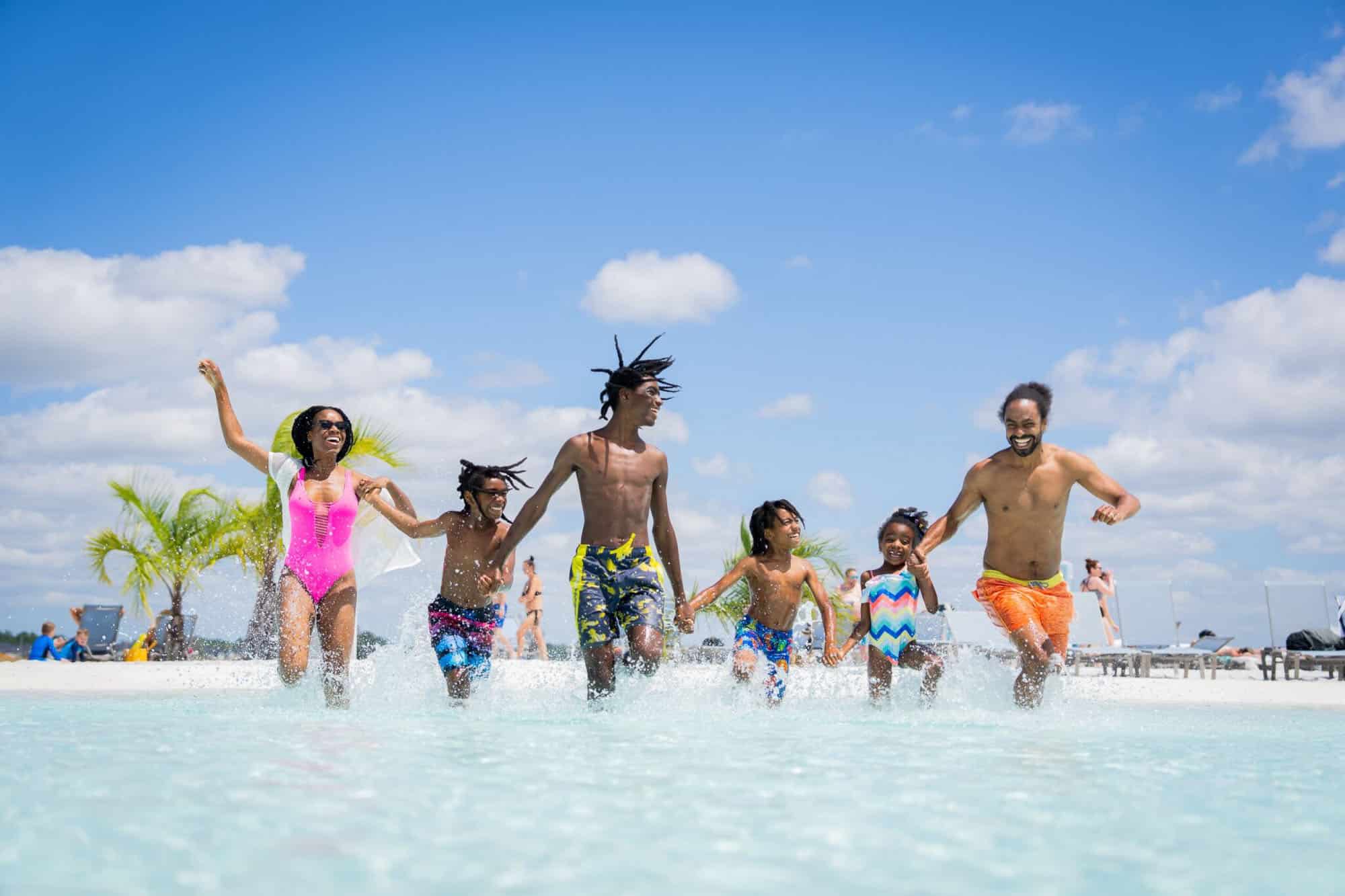 family in bathing suits walking in the water at a beach