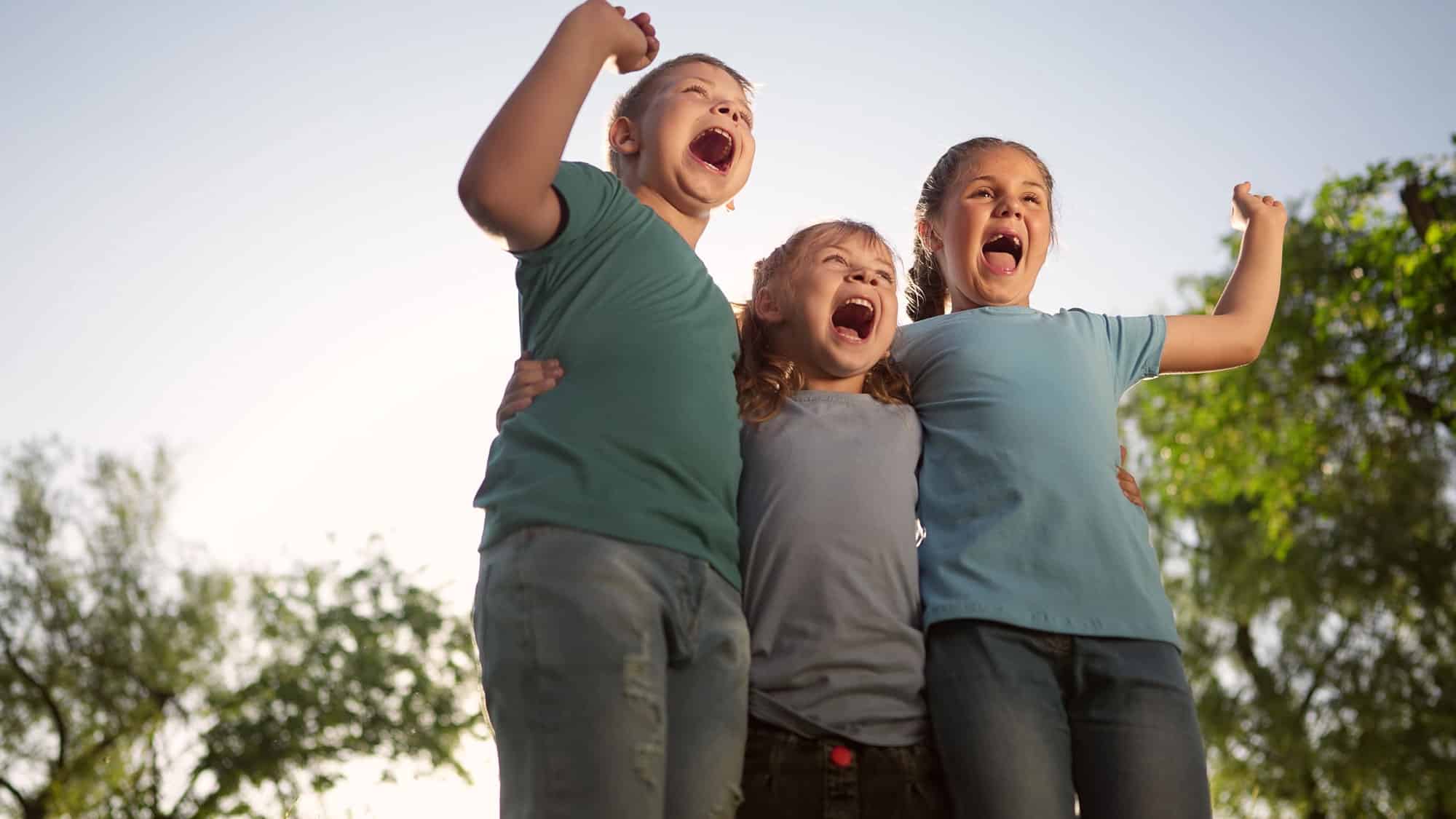 three happy children with their arms around each other